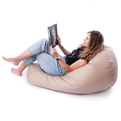 Kobieta w pozycji półleżącej, czytająca magazyn na beżowym fotelu grucha EcoYoung – pufa relaksacyjna z granulatem, odporna na warunki zewnętrzne.