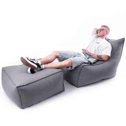 Mężczyzna relaksujący się na grafitowym zestawie Leno – nowoczesny fotel z dopasowaną pufą, doskonały na balkon lub do salonu.