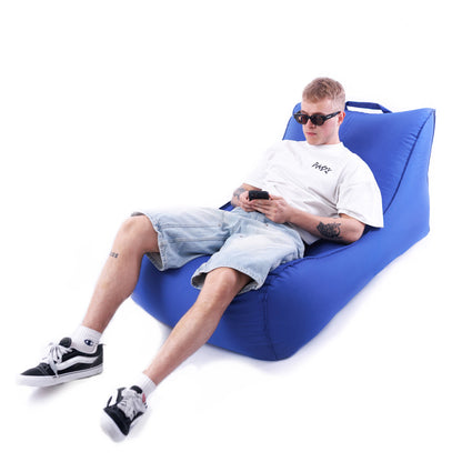 Mężczyzna siedzący na niebieskiej leżance Canvas z telefonem w ręce – wygodny fotel ogrodowy.