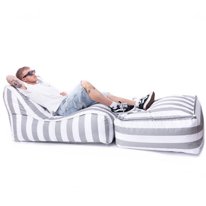 Mężczyzna wypoczywający na zestawie Stripe – leżanka i pufa w szerokie pasy, ustawione na białym tle, meble outdoor marki EcoYoung