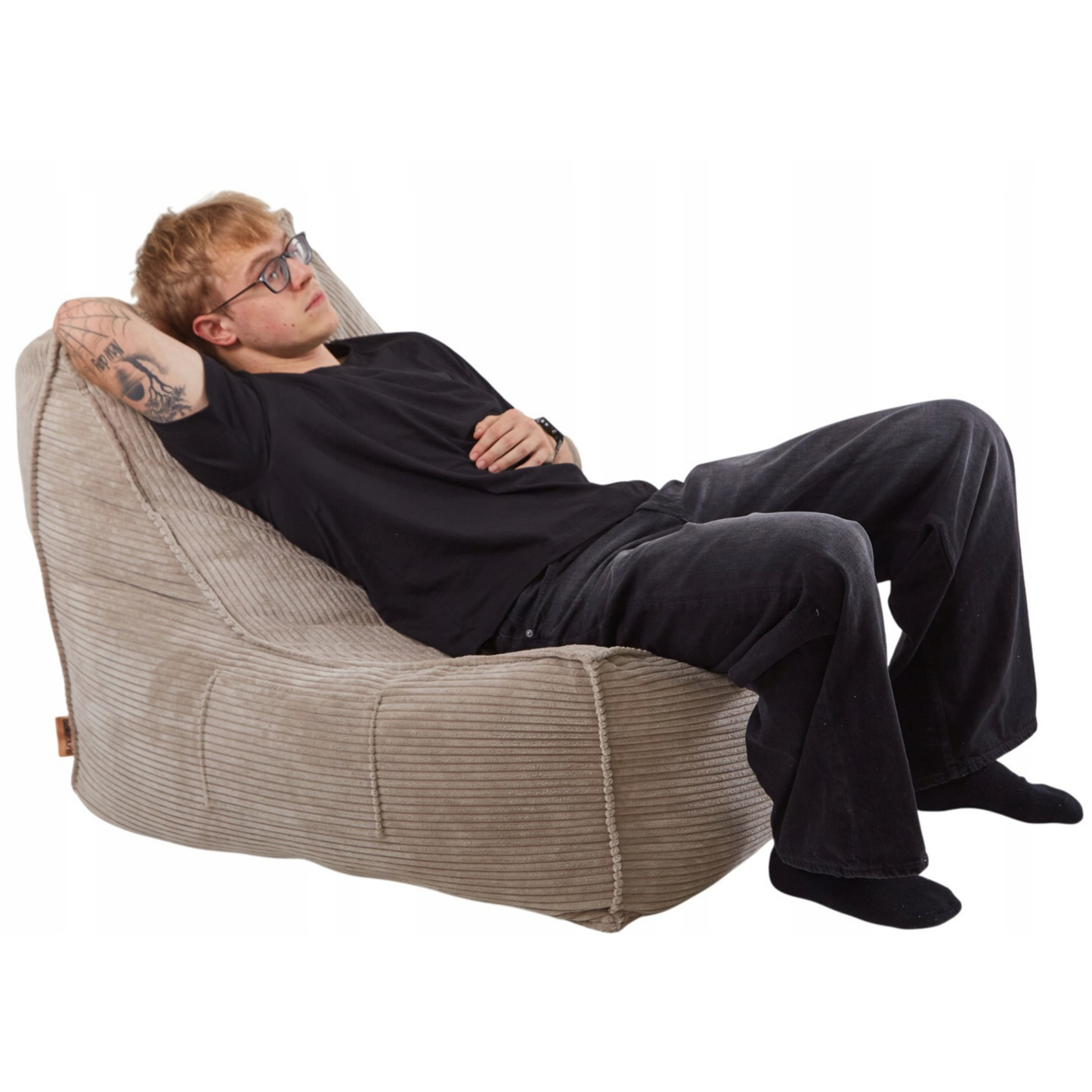 Mężczyzna odpoczywający na wygodnym fotelu LENO z tkaniny sztruksowej w kolorze beżowym.