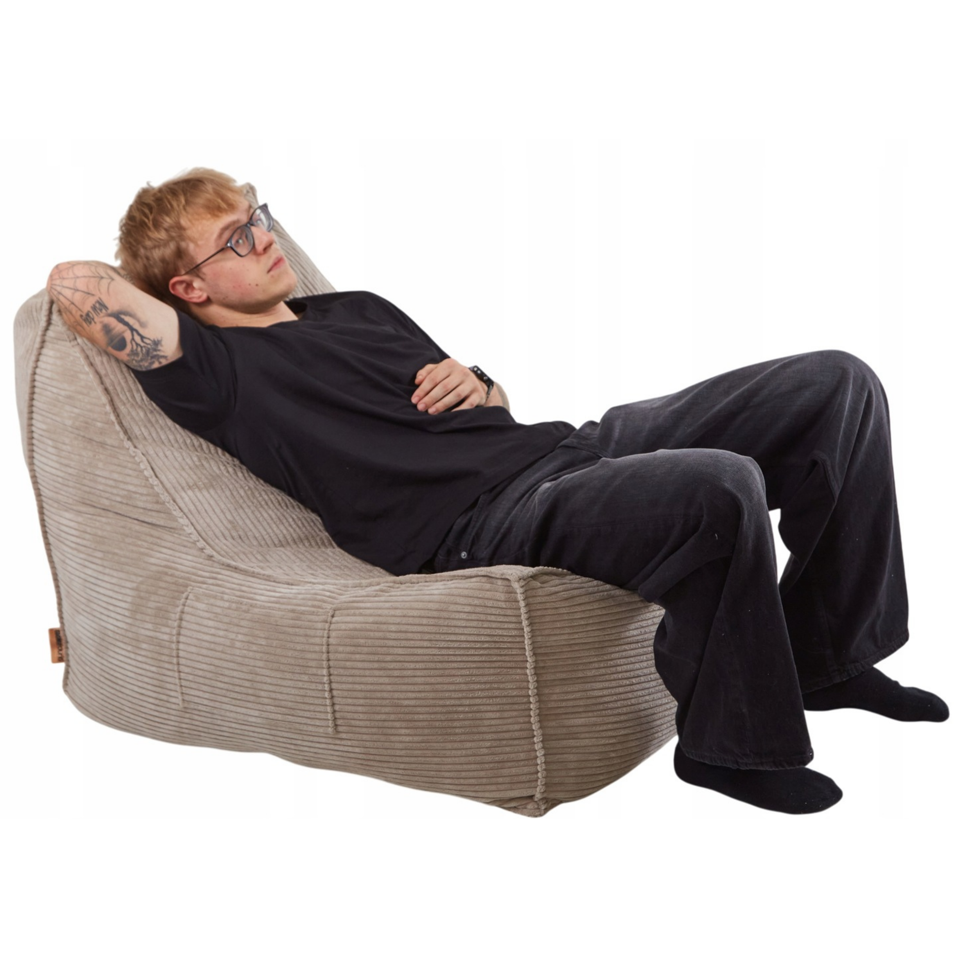 Mężczyzna odpoczywający na wygodnym fotelu LENO z tkaniny sztruksowej w kolorze beżowym.