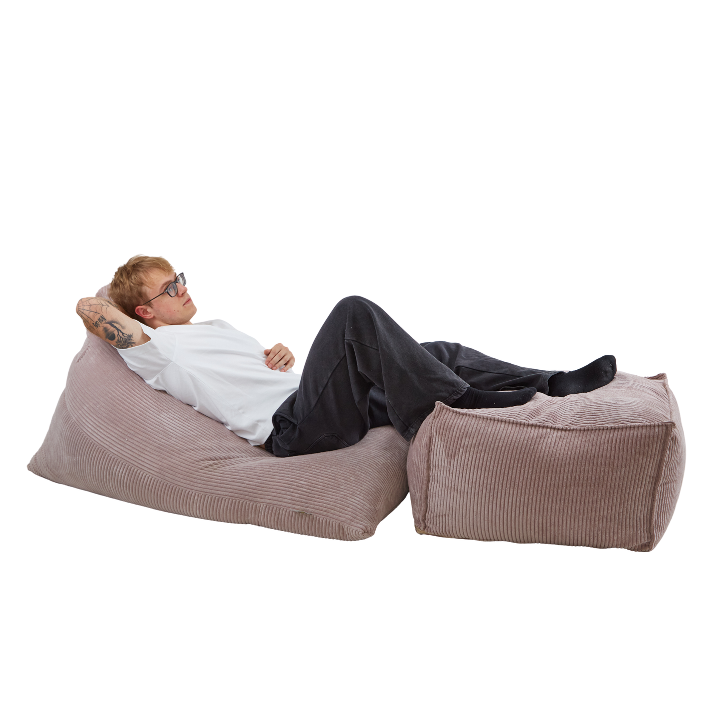 Mężczyzna relaksujący się na zestawie puf: poducha Joy + wielofunkcyjna pufa pod nogi. Komplet jest w wykonany z tkaniny sztruksowej w kolorze beżowym.