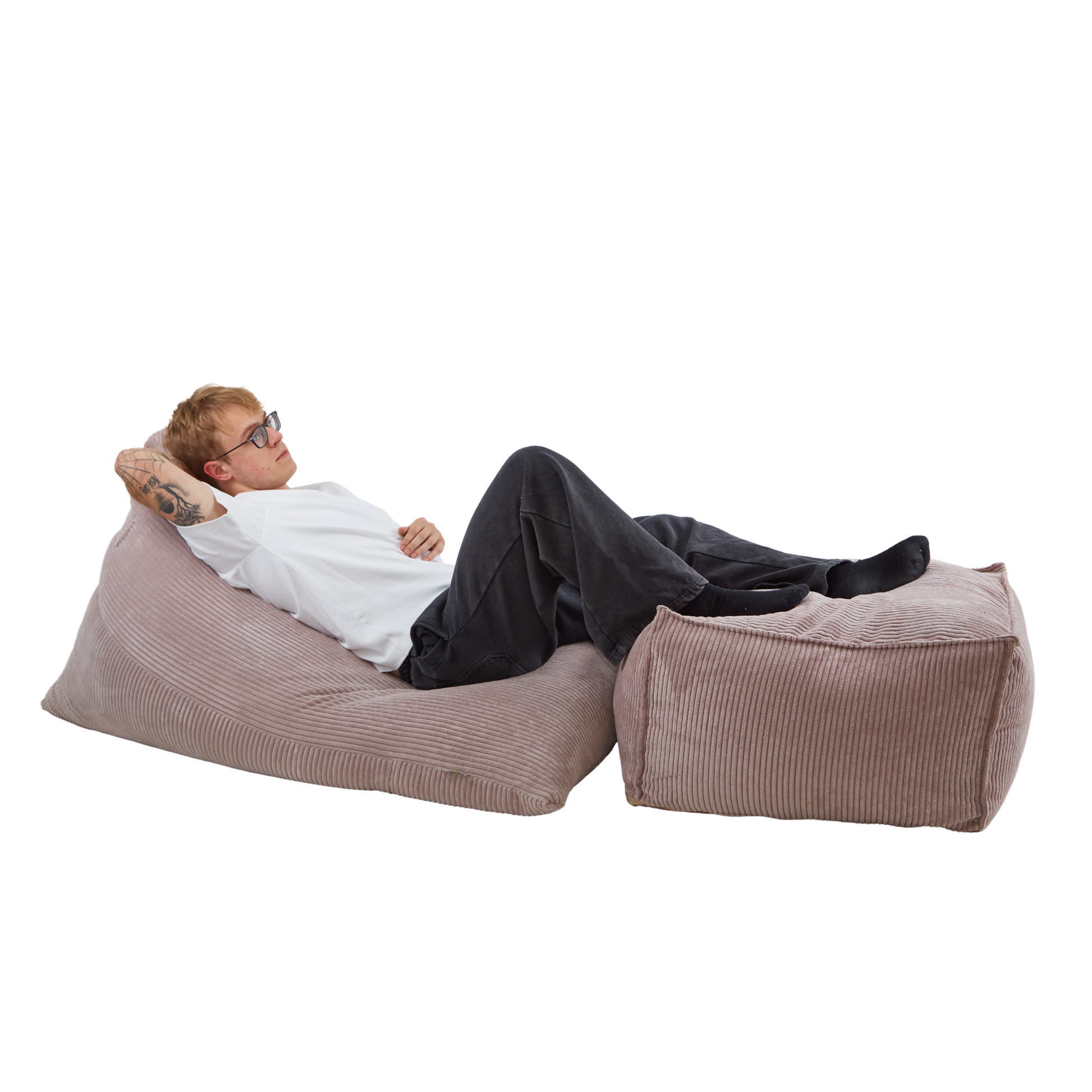 Mężczyzna relaksujący się na zestawie puf: poducha Joy + wielofunkcyjna pufa pod nogi. Komplet jest w wykonany z tkaniny sztruksowej w kolorze beżowym.